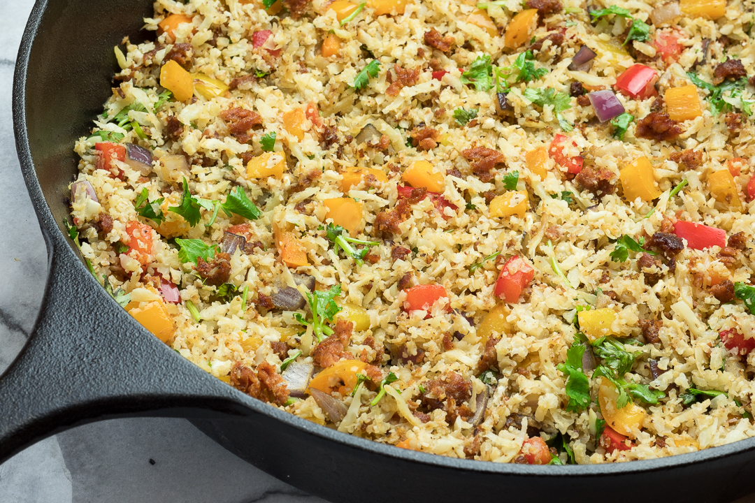 Chorizo Fried Cauliflower Rice with veggies in a cast iron skillet. 