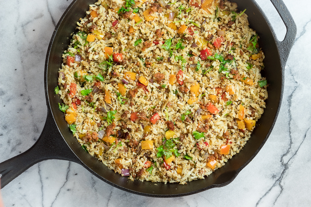 Chorizo Fried Cauliflower Rice with veggies in a cast iron skillet.