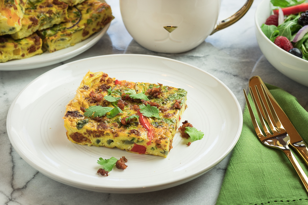 Slice of spicy chorizo fritatta plated with coffee. 