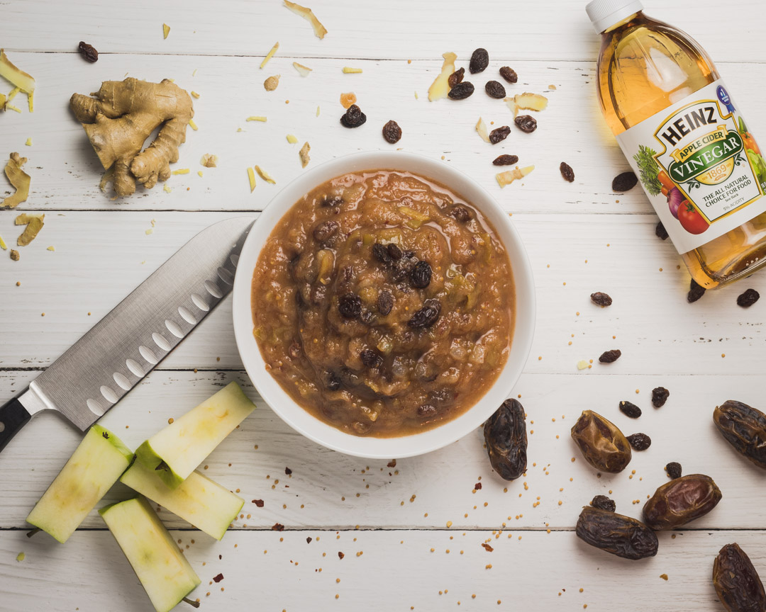 Sweet and spice apple chutney in a bowl surrounded by it's ingredients. 