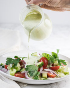 Herby ranch dressing being poured onto a salad