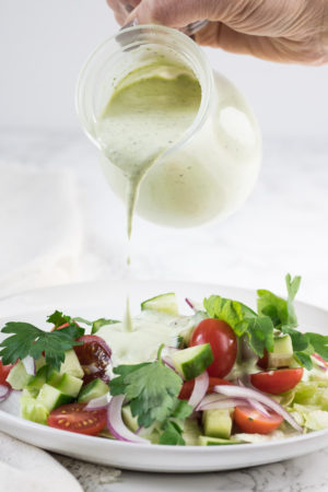Herby ranch dressing being poured onto a salad
