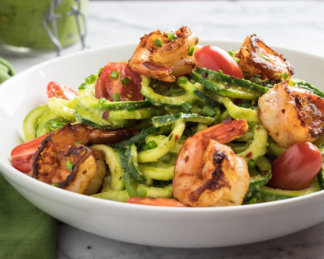 Pesto Zoodles with cajun shrimp and cherry tomatoes served in a bowl. 