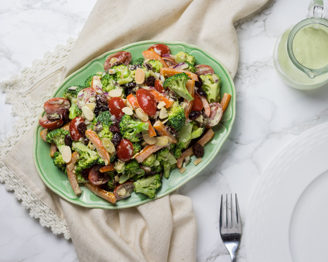 Overhead view of a colorful broccoli salad on a green plate 