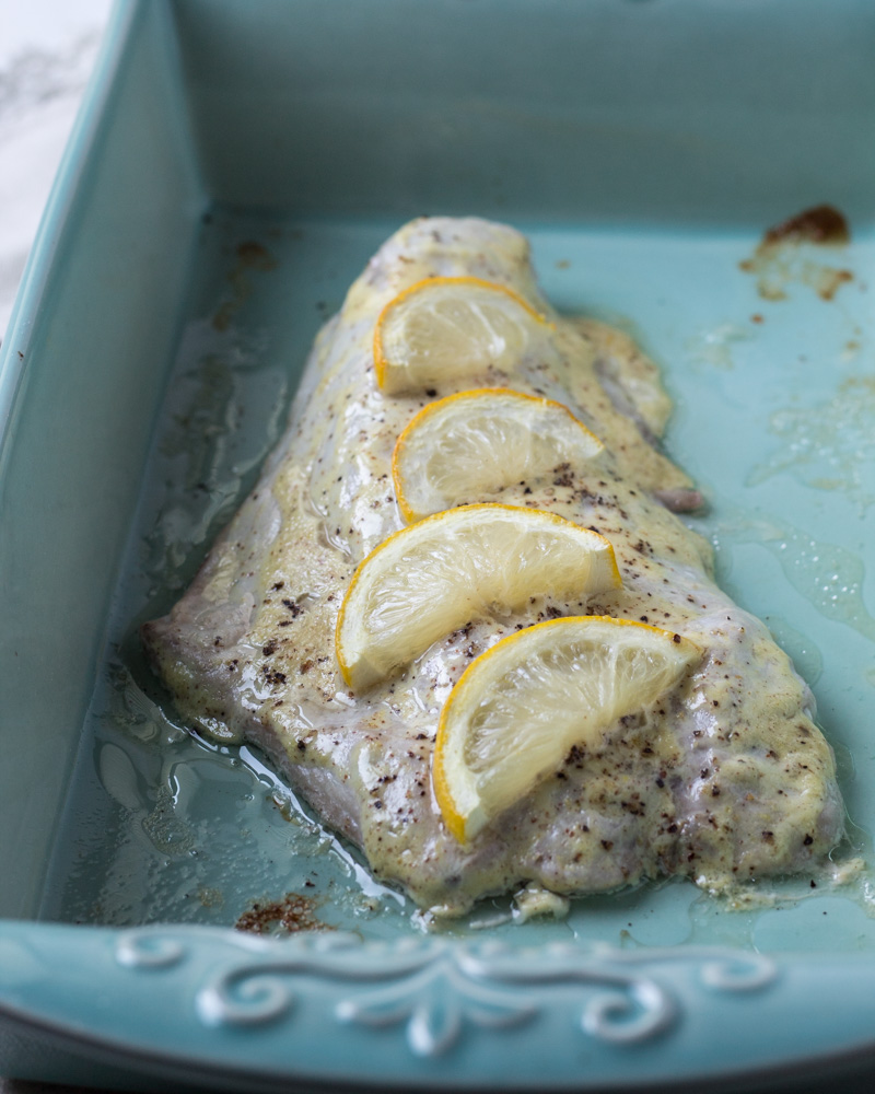 Coked bluefish fillet in a blue baking pan. 