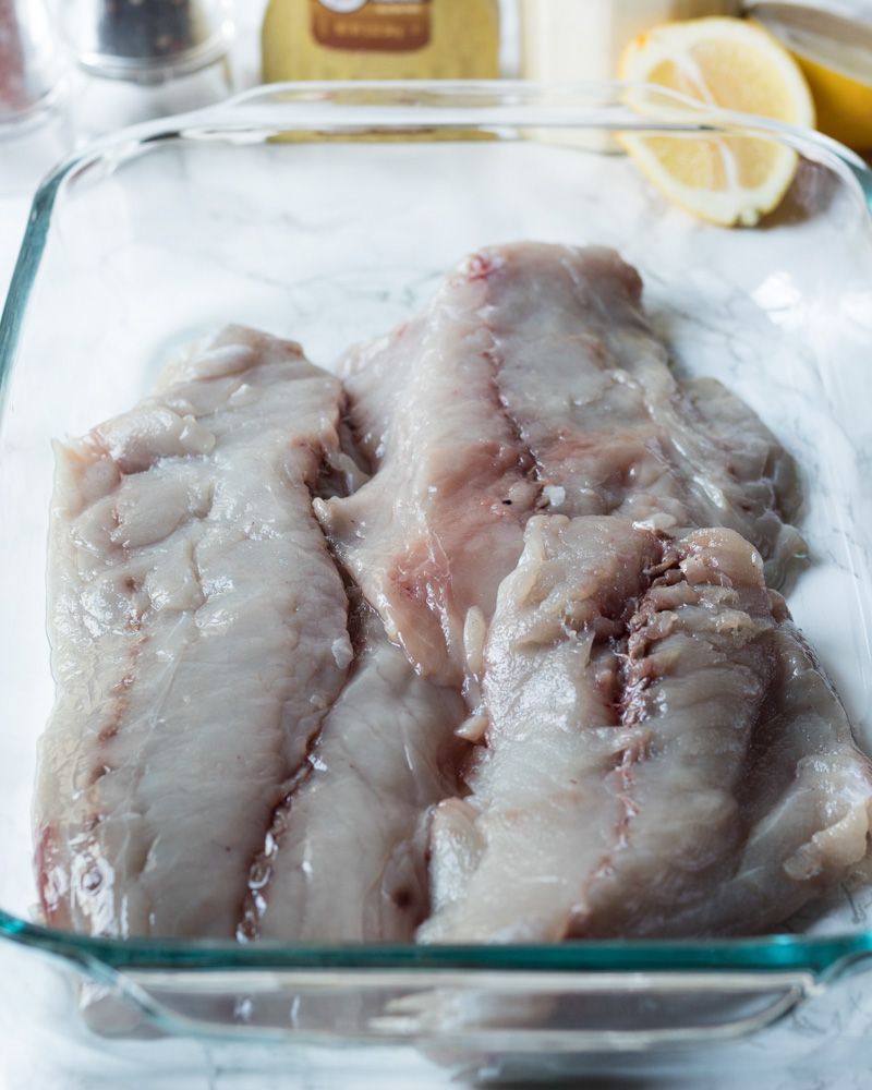 Raw bluefish fillets in a baking dish.