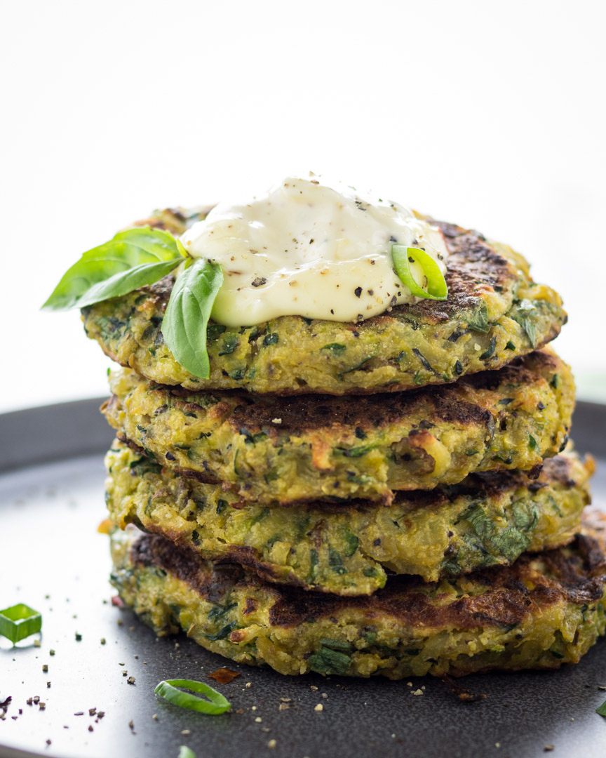 Zucchini and potato pancakes stacked high and topped with mayo