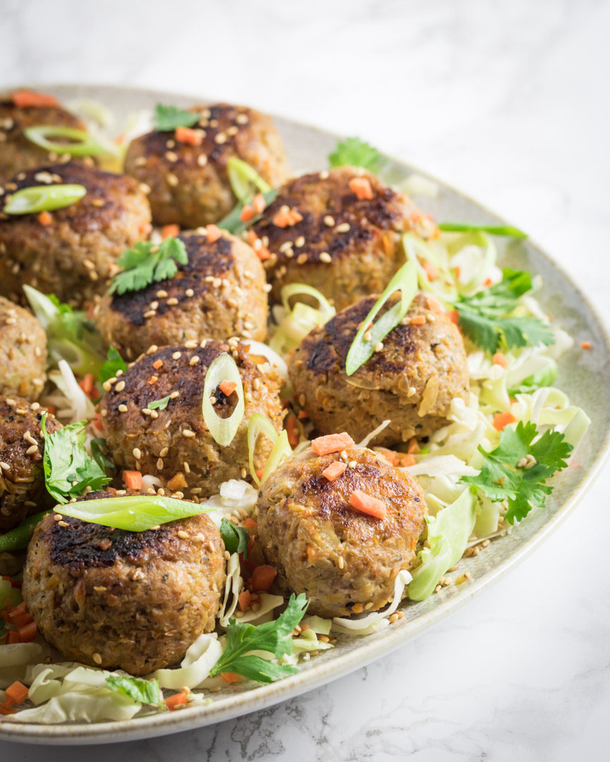 Egg Roll Meatballs on a platter topped with chopped scallions and carrots.