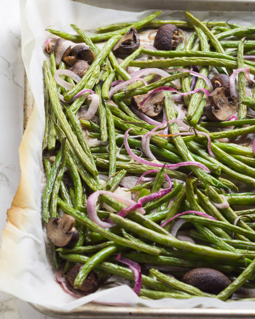 Green beans mushrooms and onions baked on a sheet pan 