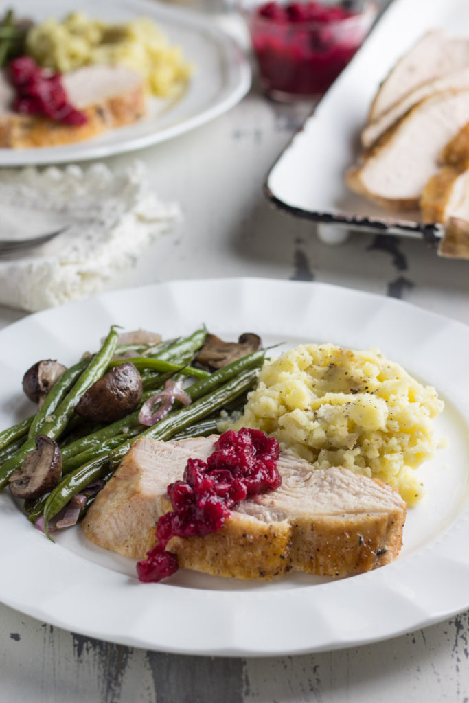 Christmas dinner on a plate with turkey, mashed potatoes, green beans and cranberry sauce 