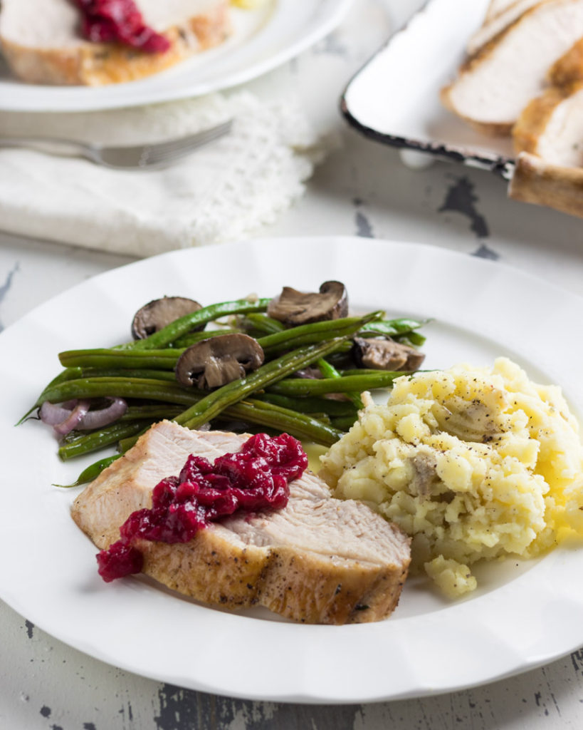 Homemade cranberry sauce on turkey with mashed potatoes and green beans