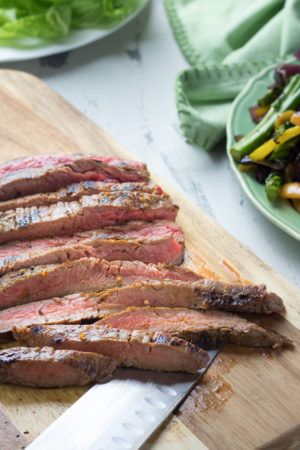 Sliced skirt steak on a cutting board with a knife